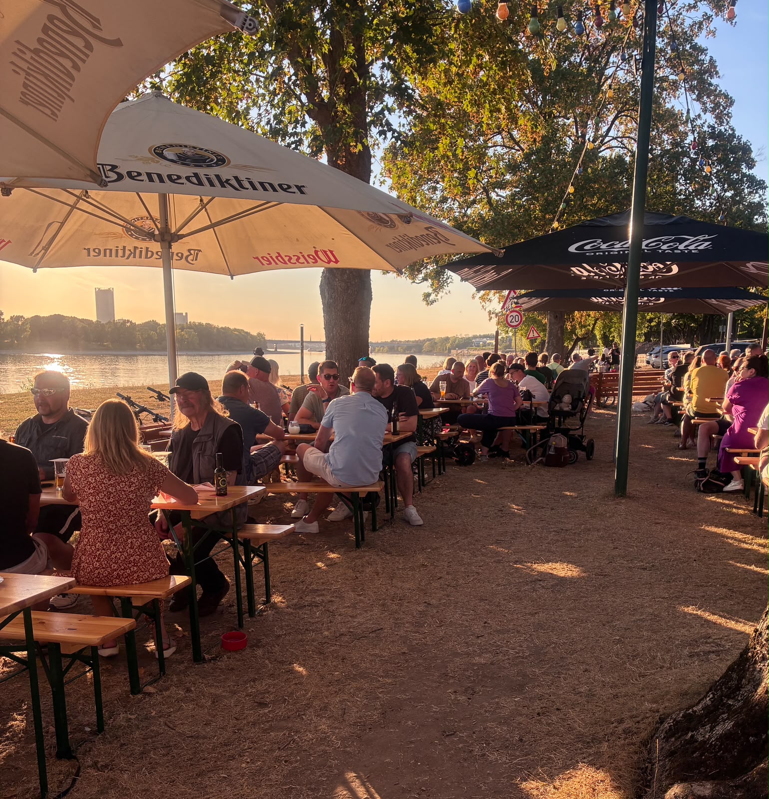 Gäste an den Biergartentischen unter Sonnenschirmen