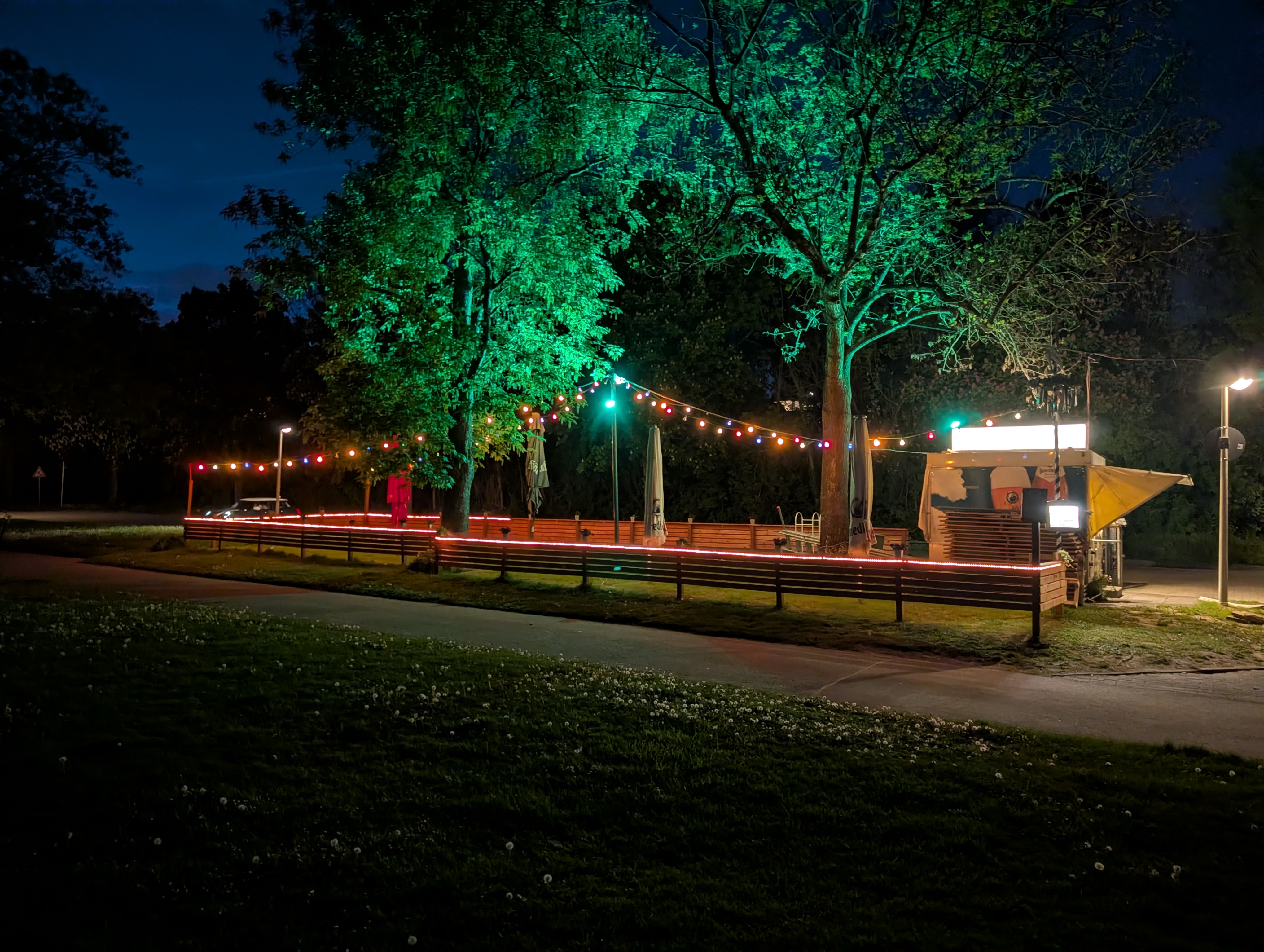 Biergarten mit beleuchteten Bäumen und bunten Lichterketten am Abend